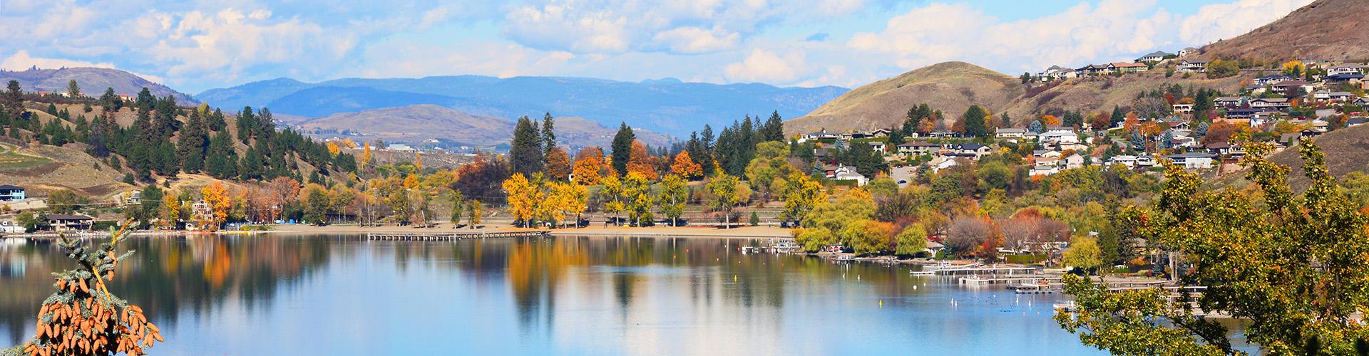 Mountains, trees, houses being reflected in a lake